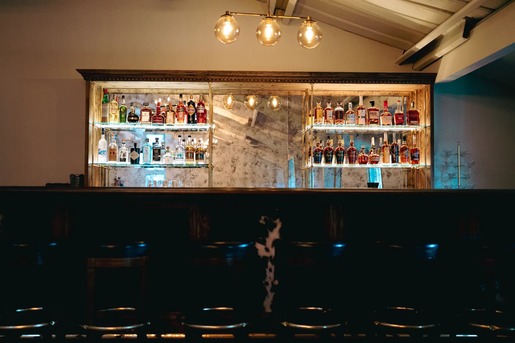 Backlit bar shelving stocked with spirits inside Heritage Hall.