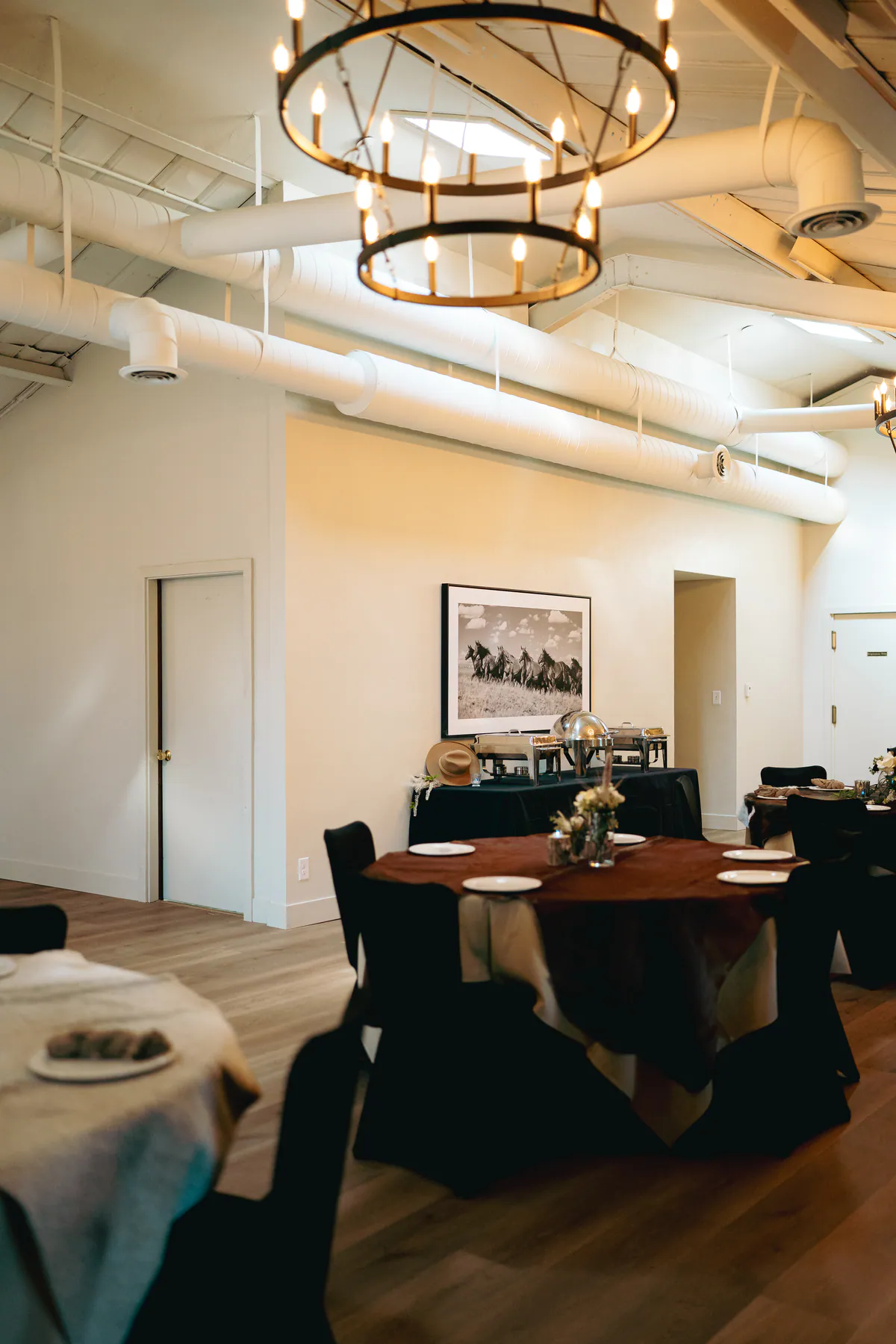 Heritage Hall dining room set with round tables under a wagon-wheel chandelier.