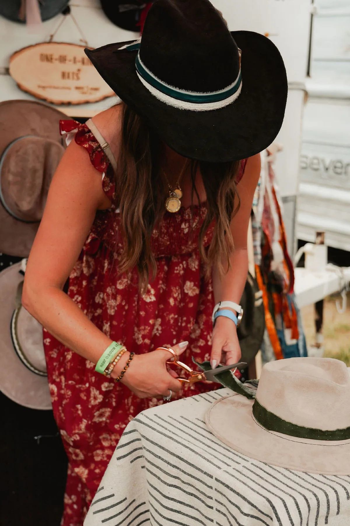 Choose the details that make the hat feel like yours. Person trimming a custom hat band while wearing a black western hat