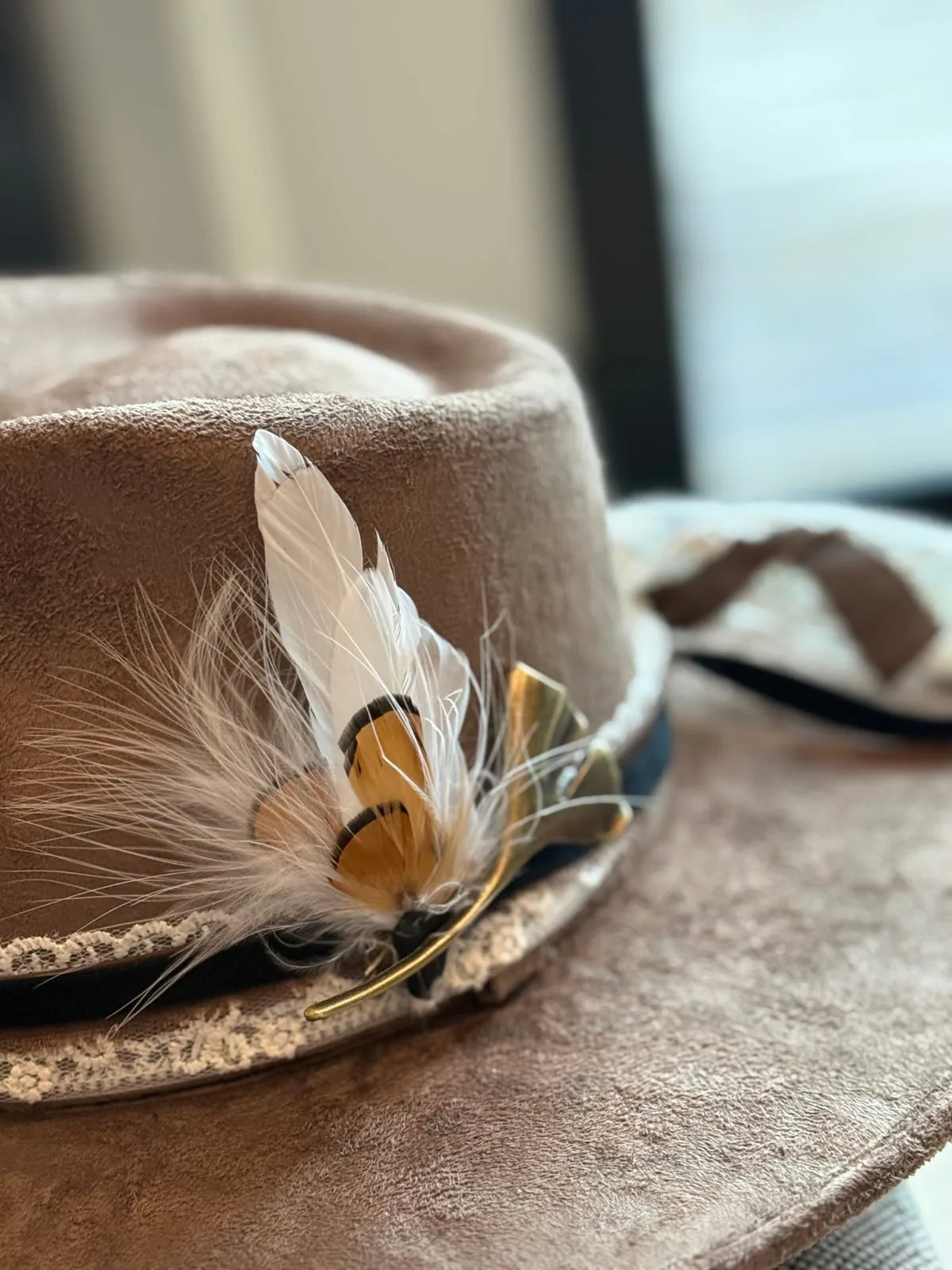 Feathers, bands, textures, and small details make the piece yours. Close-up of a cream western hat with layered feather and band details