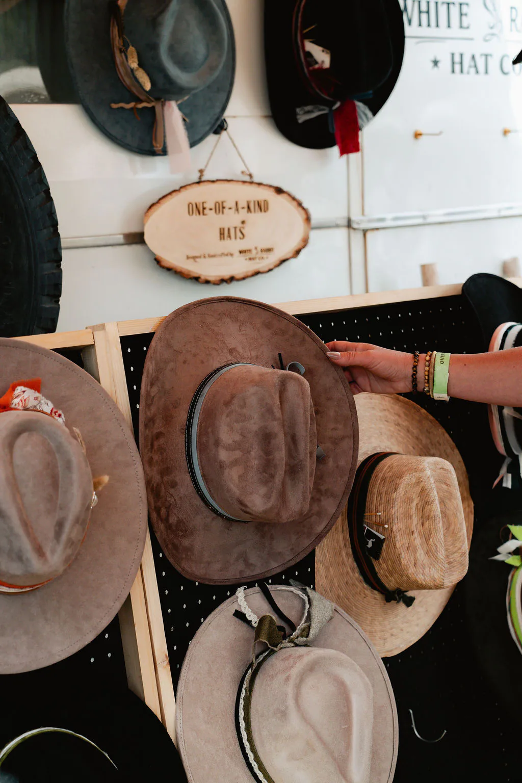 A full hat-bar setup with colors, bands, and textures to explore. White Rabbit Hat Co. display wall with western hats hanging from hooks