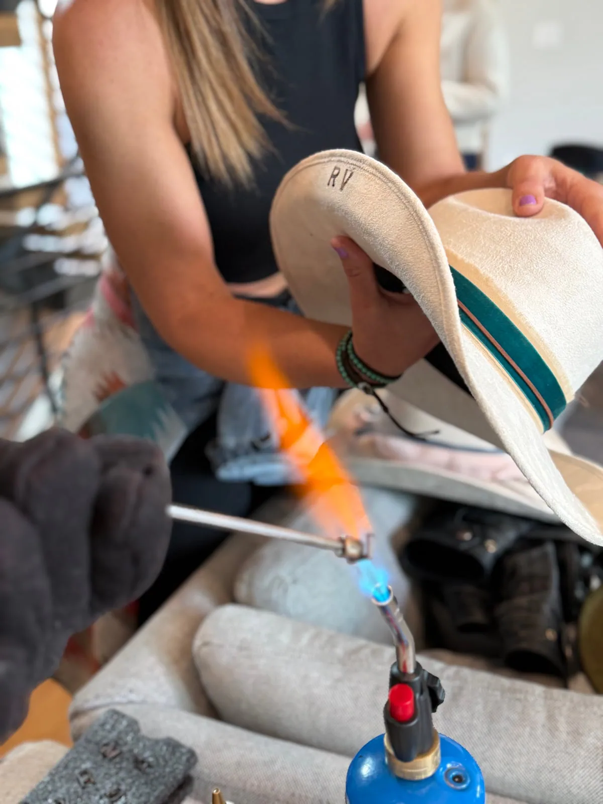 Shaping and finishing details bring each hat to life. Western hat brim being shaped over a small blue flame at the White Rabbit Hat Co. hat bar