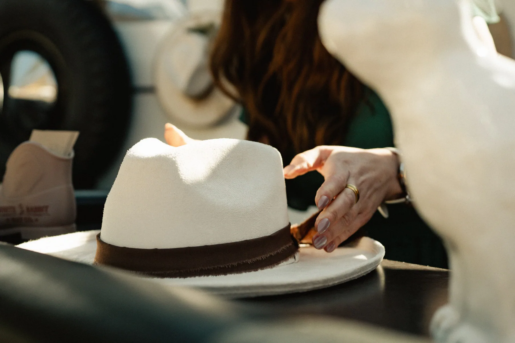Hands-on hat shaping, styling, and western details. Hands shaping the brim of a cream western hat on a work table
